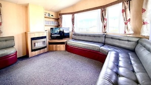 A cozy living room with a sofa, a television, and a bookshelf. - Sea Views 2 Bed - Sleeps 6 - Pets - Parking - Wifi (Longmanhill)