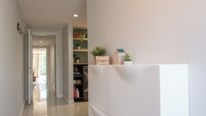 A hallway with a white door, a shelf with plants, and a 'Happy Spring' sign. - Cozy Retro Suite with Garden Walkout, Games & Lounge! (Toronto)