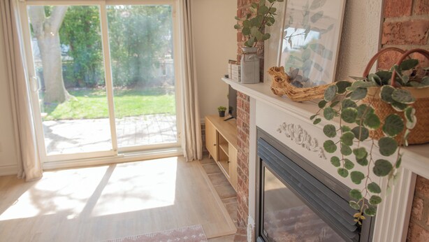 A room with a fireplace, a sliding glass door leading to a garden, and a shelf with decorative items. - Cozy Retro Suite with Garden Walkout, Games & Lounge! (Toronto)