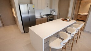 Eine moderne Küche mit einer zentralen Kochinsel, Barhocker, Edelstahlgeräten und Holzschränken.