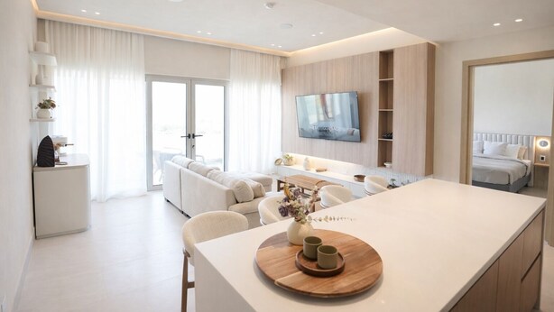 Ein modernes Wohnzimmer mit einer Couch, einem Esstisch und einem an der Wand befestigten Fernseher.
