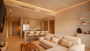 Ein modernes Wohnzimmer mit einer Couch, einem Holztisch und einer Küchenzeile mit Bar.