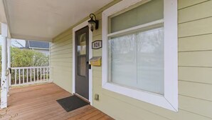 Eine Veranda mit einer Holzdiele, einer Tür, einem Fenster mit weißem Rahmen und einem Briefkasten.
