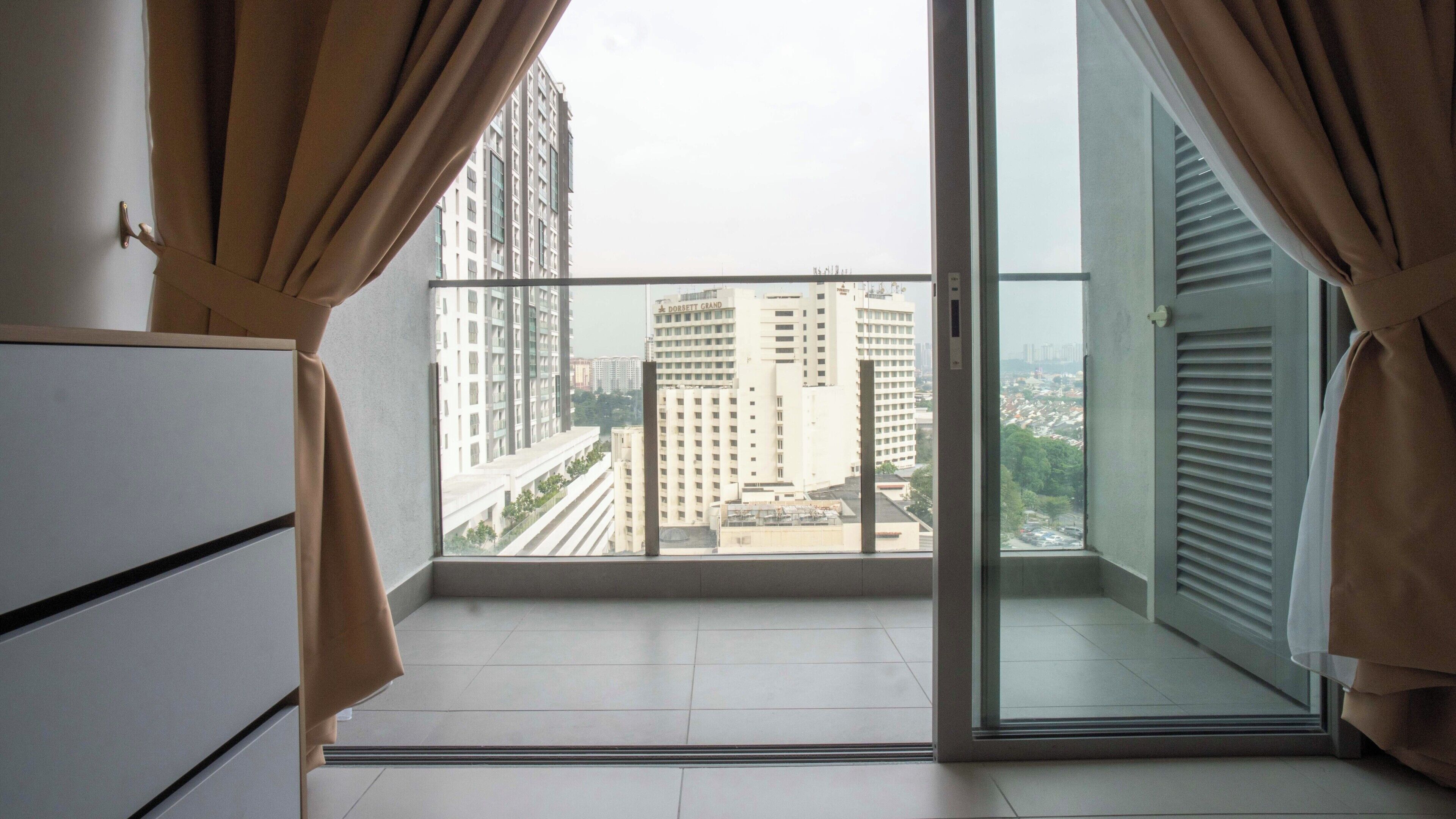 Un balcon avec vue sur la ville, une porte-fenêtre coulissante et un meuble blanc.