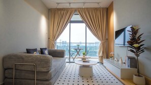 A modern living room with a sofa, a coffee table, and a TV. - Dorsett Waterfront Subang by Guestonic (Subang Jaya)