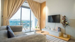 Ein modernes Wohnzimmer mit Sofa, Couchtisch, Fernseher und einem Balkon mit Blick auf die Stadt.