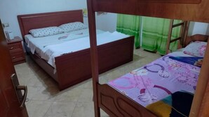 A room with two wooden beds, a nightstand, and a door. - Backpackers La Casa De Payaso (Durres)