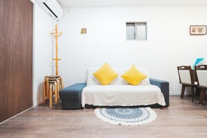 Une pièce avec un lit, une petite table, une chaise, une fenêtre et une porte.