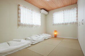 A room with tatami mats, a bed, a massage table, a massage chair, a wall-mounted air conditioner, and a standing heater.