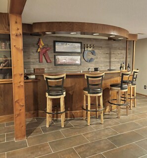 Eine Bar mit Holzhockern, einer gebogenen Theke und gerahmten Bildern an der Wand.