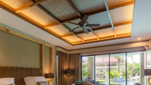 A hotel room with a large bed, a sofa, a desk, and a view of a pool and greenery. - The Gantari Ubud Bali (Ubud)