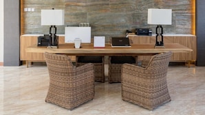 A modern reception desk with two computer stations, a calendar, and a printer. - The Gantari Ubud Bali (Ubud)