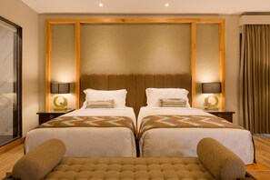 Une chambre double avec deux lits, des tables de chevet, des lampes et une grande fenêtre avec des rideaux.