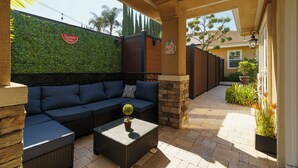An outdoor patio with a sofa, a coffee table, and a wall with greenery.
