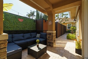 Eine Terrassengruppe mit Sofa, Couchtisch und einer Wand mit Pflanzen.