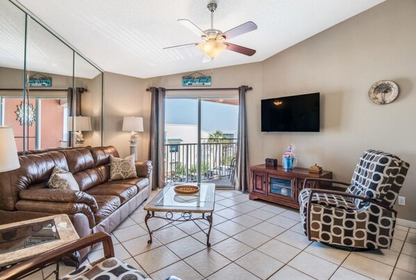A living room with a leather sofa, patterned armchair, and a coffee table. - Free Beach Service! - Miramar Mainstay (Miramar Beach)