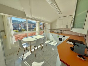 Eine moderne Küche mit Essbereich, einer Waschmaschine und Blick auf die Stadt.