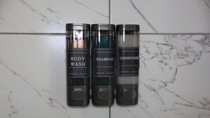 Three bottles of body wash, shampoo, and conditioner on a tiled wall. - Cozy 1-bedroom apartment in lovely Dallas with AC (Dallas)