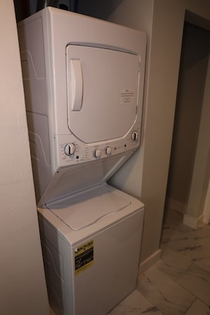 Lavadora y secadora apilables con panel de control, etiqueta ENERGY GUIDE y puerta con manija.
