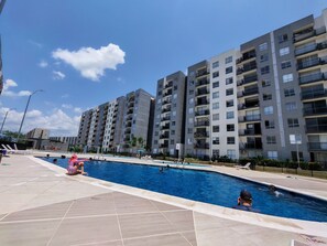 Una piscina rodeada de edificios residenciales de varios pisos con balcones.