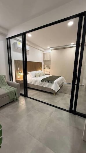 A modern bedroom with a bed, a chair, and a nightstand. - Coralina Paraíso Suite (Santa Marta)