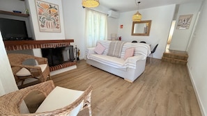 Ein Wohnzimmer mit einer Couch, Korbstühlen, einem Kamin, einem Fernseher und Kunstwerken an den Wänden.