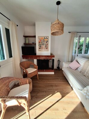 Ein Wohnzimmer mit Kamin, Korbsesseln, einer Couch und einer Pendelleuchte.