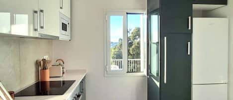 A modern kitchen with a large window, wooden flooring, and a built-in oven.