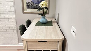 Un tavolo da pranzo con un vaso di fiori, un quadro appeso alla parete e una parete in mattoni.