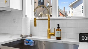 Eine Küche mit einem goldenen Wasserhahn, einem Papierhandtuchhalter, einem Seifenspender und einer Seifenschale.