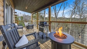 Una terraza de madera con mobiliario exterior, una parrilla y un brasero.