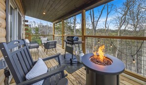 Eine Holzterrasse mit Gartenmöbeln, einem Grill und einer Feuerstelle.