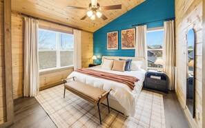Ein Schlafzimmer mit Bett, Sitzbank, Nachttischen und Bildern an der Wand.