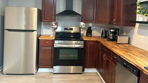 A kitchen with a stainless steel refrigerator, a built-in oven, a coffee maker, and wooden cabinets. - Tranquil 3-bedroom house in Syracuse perfect for your getaway (Syracuse)