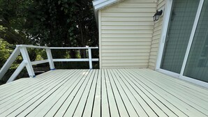 A wooden deck with white railings, a beige house, and a window with a grid pattern. - Tranquil 3-bedroom house in Syracuse perfect for your getaway (Syracuse)