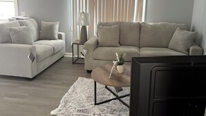 A living room with two sofas, a coffee table, a lamp, and a TV. - Tranquil 3-bedroom house in Syracuse perfect for your getaway (Syracuse)