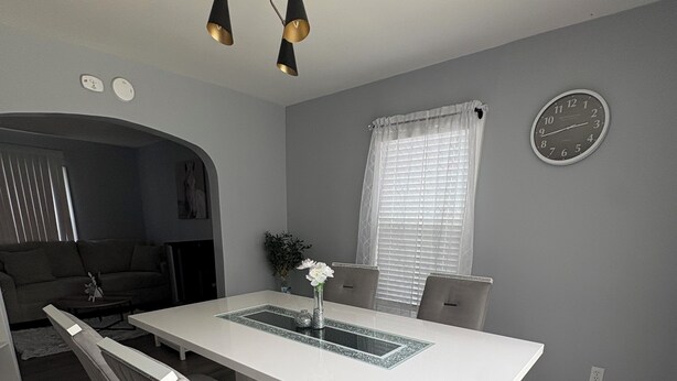 A modern dining area with a white table, grey walls, and a ceiling light fixture. - Tranquil 3-bedroom house in Syracuse perfect for your getaway (Syracuse)