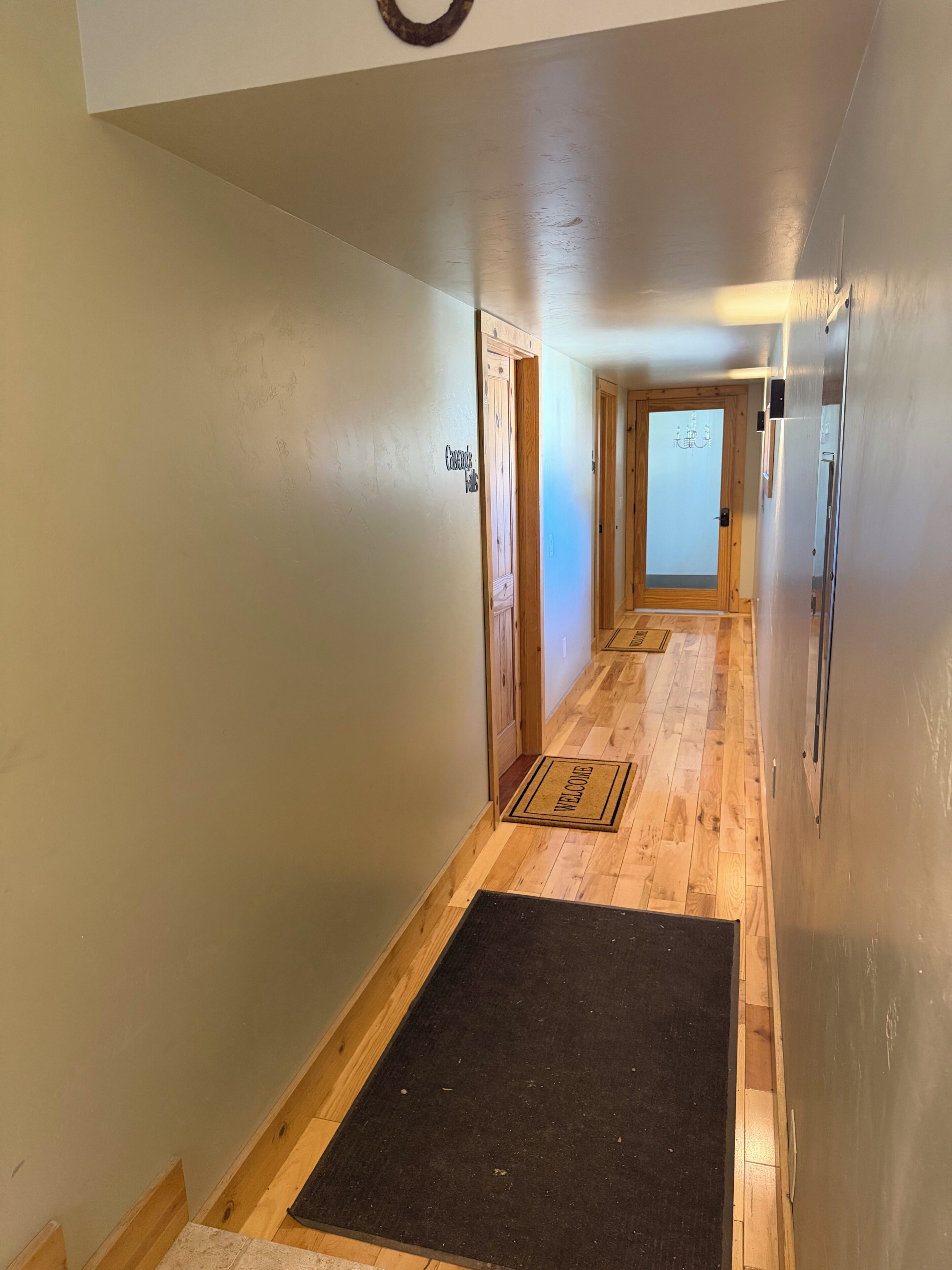Un pasillo con piso de madera, un felpudo y una puerta con el letrero de 'Google'.