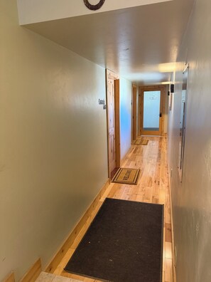 Un couloir doté d’un plancher en bois, d’un paillasson et d’une porte sur laquelle est apposé un panneau indiquant « Google ».