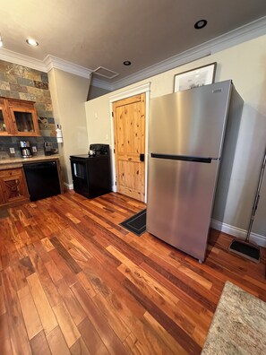 Una cocina con refrigerador de acero inoxidable, armarios de madera, cafetera y lavavajillas.