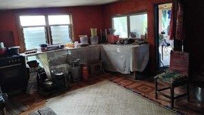 A compact kitchen with a stove, sink, and windows.