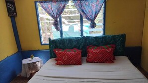 A room with a bed, a small round table, and a window with curtains.