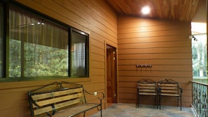 A wooden cabin interior with a bench, two chairs, a window with curtains, a door, and a tiled floor. - Spacious Monteverde Bird-watchers Home (Monteverde)