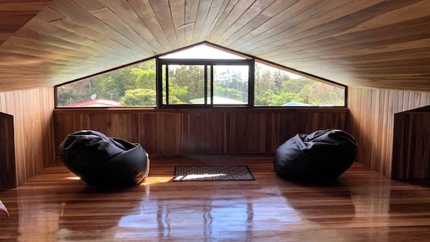 A room with wooden slatted ceiling, two bean bags, a small rug, and large windows with a view of greenery. - Spacious Monteverde Bird-watchers Home (Monteverde)