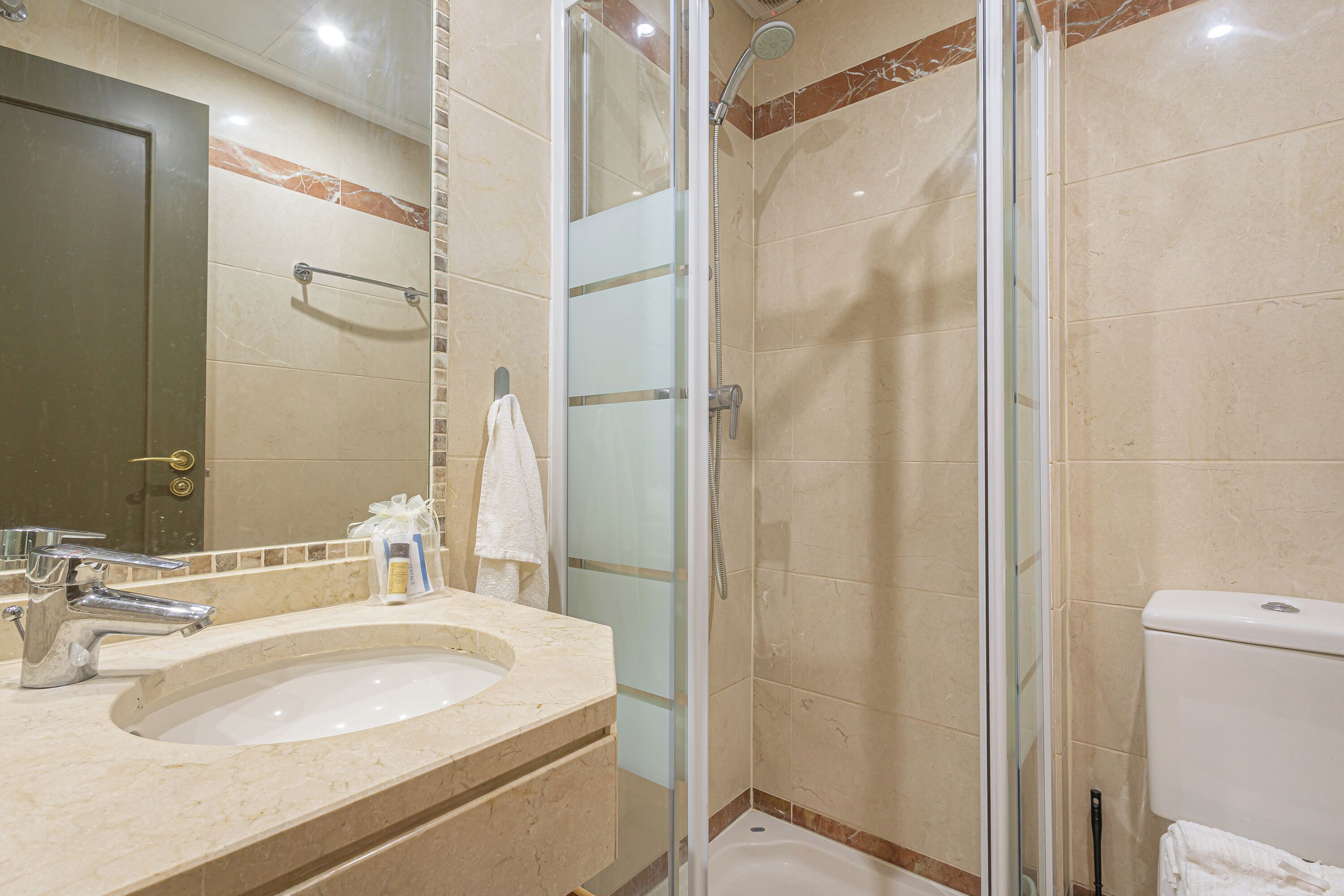 A bathroom with a sink, mirror, shower, and toilet.