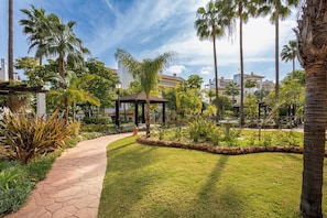 A paved pathway, a gazebo, and palm trees in a landscaped garden area. - Calanova Grand Golf, La Cala de Mijas, Spain (La Cala de Mijas)
