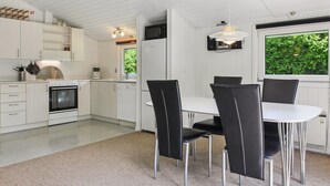 Una cucina moderna con mobili bianchi, un tavolo da pranzo con sedie nere e un'ampia finestra vista sul verde.