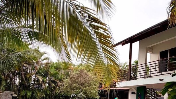A swimming pool with water features, surrounded by palm trees and a building with a balcony. - Luxury house in Villavicencio, just 10 mins from the city surrounded by nature. (Villavicencio)
