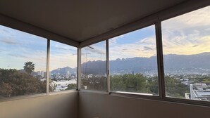 A room with a large window overlooking a cityscape and mountains. - Apartment in San Pedro Super Central and Safe Zone (San Pedro Garza García)