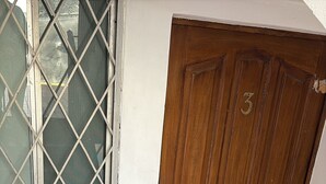 A wooden door with a number '3' and a keypad lock, a window with a metal grid, and a white metal gate. - Apartment in San Pedro Super Central and Safe Zone (San Pedro Garza García)